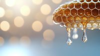 Fresh honey drips from natural honeycomb structure with golden bokeh background, showcasing organic sweetness and natural food production in macro photography.