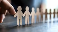 Finger touching wooden human chain figures standing in row on reflective surface, symbolizing leadership, teamwork, community support and human connection.