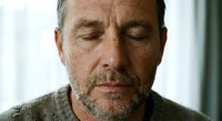 Middle-aged Caucasian man with beard and freckles in peaceful meditation pose with closed eyes, expressing mindfulness and inner calm for wellness concepts.