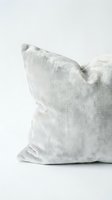 Soft gray velvet cushion with plush texture on white background, evoking luxury home decor and cozy interior styling concepts.