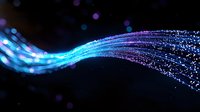 Glowing blue and purple light stream with sparkling particles flowing in curved motion against dark background, creating magical luminous effect.