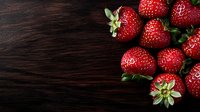 Fresh ripe strawberries scattered on dark wooden background, top view composition with copy space for text. Natural food photography.
