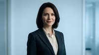 Professional businesswoman in dark suit standing confidently in modern office environment with natural lighting for corporate presentations.