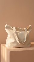 Cream canvas tote bag with handles displayed on a beige pedestal against a neutral background. Suitable for fashion, retail, and product mockup designs.