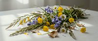 Dried flower arrangement featuring purple statice and yellow button blooms mixed with natural greenery and grasses on white surface for floral design and decoration.