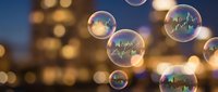 Colorful soap bubbles floating against blurred city lights background with warm golden bokeh creating dreamy atmospheric scene for creative projects.