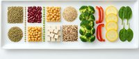 Healthy food ingredients arranged in white compartments featuring legumes, grains, fresh vegetables and citrus slices for balanced nutrition and meal planning.