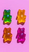 Colorful gummy bear candies on pink background with dramatic shadows. Green, yellow, orange and pink translucent jelly bears arranged in minimal composition.