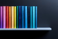 Colorful book spines arranged in rainbow spectrum order on white shelf against dark background, creating minimalist gradient composition for education concepts.