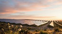 Rows of solar panels installed on rural hillside landscape at golden hour sunset, generating renewable clean energy for sustainable power production.