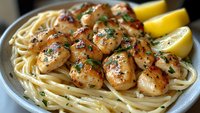 Pan-seared scallops with herbs served over linguine pasta with lemon wedges, gourmet seafood dinner plate ready for fine dining restaurant menu.