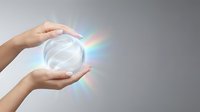 Hands holding glowing crystal sphere with rainbow light refraction, representing energy, innovation, and future technology concepts for business and wellness applications.