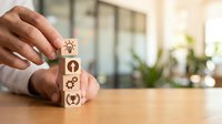 Professional hand stacking wooden blocks with innovation icons representing creative business strategy and growth mindset in modern office environment.
