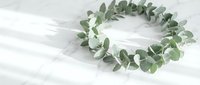 Fresh eucalyptus wreath on white marble surface for natural home decor and botanical styling projects.