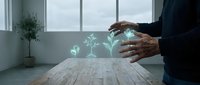 Professional businessman hands nurturing holographic green plants emerging from wooden surface in modern office environment symbolizing growth and sustainability.