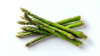 Fresh green asparagus spears arranged on white background, raw organic vegetables isolated for culinary and healthy eating concepts.