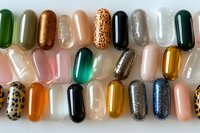 Colorful nail polish samples in capsule shapes displaying various finishes including glitter, metallic, leopard print and solid colors for beauty salon use.