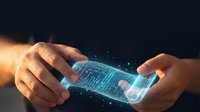 Hands holding futuristic holographic smartphone with glowing digital interface and data particles on dark background for technology concepts.