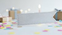 White paper banner with colorful confetti scattered on table surface for party celebration and festive event decoration with soft bokeh lights.
