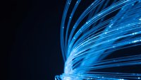 Blue fiber optic cables with glowing light streaks creating dynamic motion effect on dark background for technology and communication concepts.