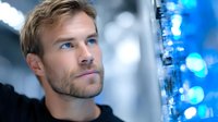 Young Caucasian male engineer examining blue LED light panel in modern laboratory setting for technology research and development projects.