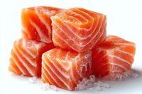 Fresh raw salmon cubes with visible marbling on white background, ready for cooking in sushi, poke bowls, or gourmet seafood dishes.
