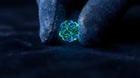 Gloved hands holding glowing green molecular structure on dark surface, representing scientific research, biotechnology, nanotechnology, and innovation in laboratory settings.