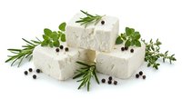 Fresh white cheese cubes with aromatic herbs rosemary thyme oregano and black peppercorns on white background for culinary cooking and gourmet food design.