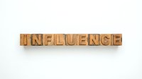 Wooden letterpress blocks spelling INFLUENCE on white background for typography and marketing design projects.