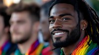 Young African American man with dreadlocks and beard smiling warmly at pride celebration, wearing rainbow flag colors, representing diversity, inclusion and LGBTQ+ community support.