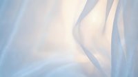 Soft flowing white fabric with gentle folds and creases creating elegant waves and shadows on light blue background for textile design projects.