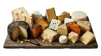 Gourmet cheese platter with variety of artisanal cheeses on rustic wooden board isolated on white background for culinary design and food photography.