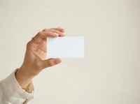 Hand holding blank white business card on neutral background, suitable for branding, corporate identity, and marketing presentations.