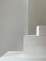 Minimalist white geometric shapes casting soft shadows on light background, abstract architectural composition with clean lines and subtle texture details.