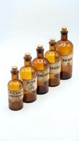 Vintage amber glass apothecary bottles with cork stoppers and aged labels arranged in row on white background for pharmaceutical design projects.