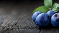 Fresh ripe blueberries with green leaves on dark wooden background, selective focus. Natural organic berries macro photography for food design.