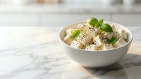 Fresh homemade vanilla ice cream scoops with mint leaves and sesame seeds in white bowl on marble counter for dessert menu and culinary photography.