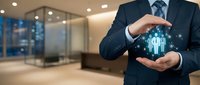 Professional businessman in dark suit protecting glowing human resources icons with hands in modern office environment for corporate leadership concepts.