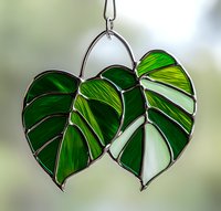Stained glass monstera leaves pendant in vibrant green tones with metal frame, handcrafted suncatcher for window display and home decoration.