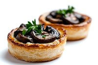 Savory mushroom tartlets with flaky puff pastry, garnished with fresh parsley. Golden brown pastry shells filled with sauteed mushrooms create elegant appetizers.