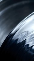 Close-up of metallic car wheel rim with chrome finish and dark tones, showcasing automotive design details for vehicle customization and transportation concepts.