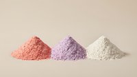 Three colorful powder piles in coral pink, lavender purple and cream white arranged on neutral beige background for cosmetic and wellness applications.