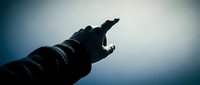 Silhouette of hand reaching toward bright light with dramatic blue gradient background creating powerful spiritual and hope concept for motivation designs.