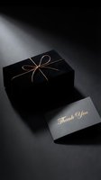 Elegant black gift box tied with rose gold ribbon beside a dark thank you card with gold script lettering on moody background.