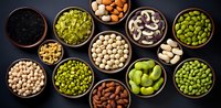 Variety of legumes and seeds in wooden bowls on dark background. Collection of different types of beans, peas, lentils and nuts arranged in rustic style.