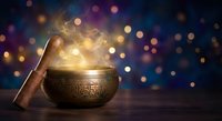 Mystical singing bowl with glowing light and magical smoke against colorful bokeh background for meditation, spiritual healing and wellness practices.