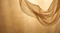 Flowing golden brown silk fabric with elegant drapes and soft lighting creates luxurious textile background for fashion and beauty design projects.