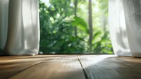 Sunlight streaming through white curtains onto wooden floor, creating serene home atmosphere with green garden view outside.