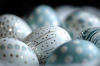 Delicate blue and white Christmas ornaments with metallic polka dot pattern create festive holiday mood on dark background with soft bokeh effect.