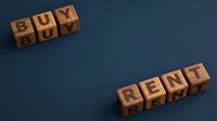 Wooden blocks spelling buy and rent on blue background, representing real estate investment decision and property market choice.